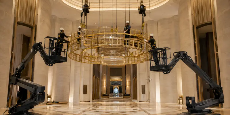 Professional installation of a large chandelier in a high-ceiling hotel lobby Professional installation of a large chandelier in a high-ceiling hotel lobby