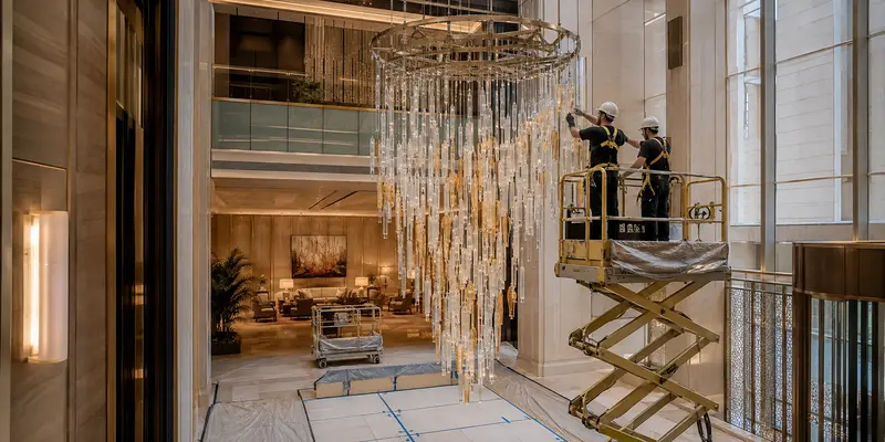 Professional installation of a large chandelier in a hotel atrium