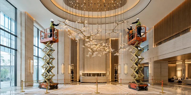 Installation of custom designed luxury chandeliers in a high-ceiling interior
