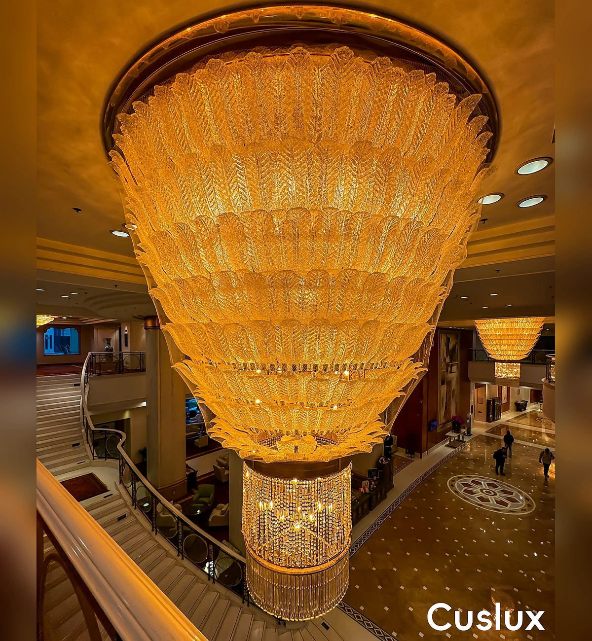 1787724177423916.webp layered handmade glass leaf chandelier with warm lighting.webp